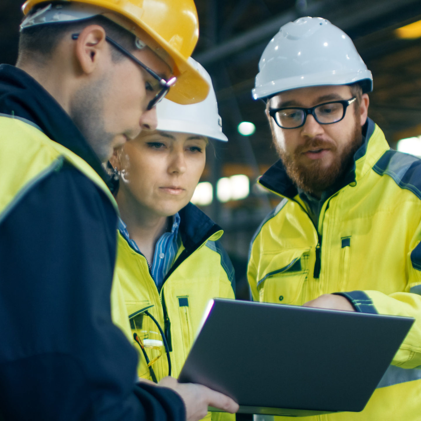 female engineer and two male colleagues studying a laptop at building site