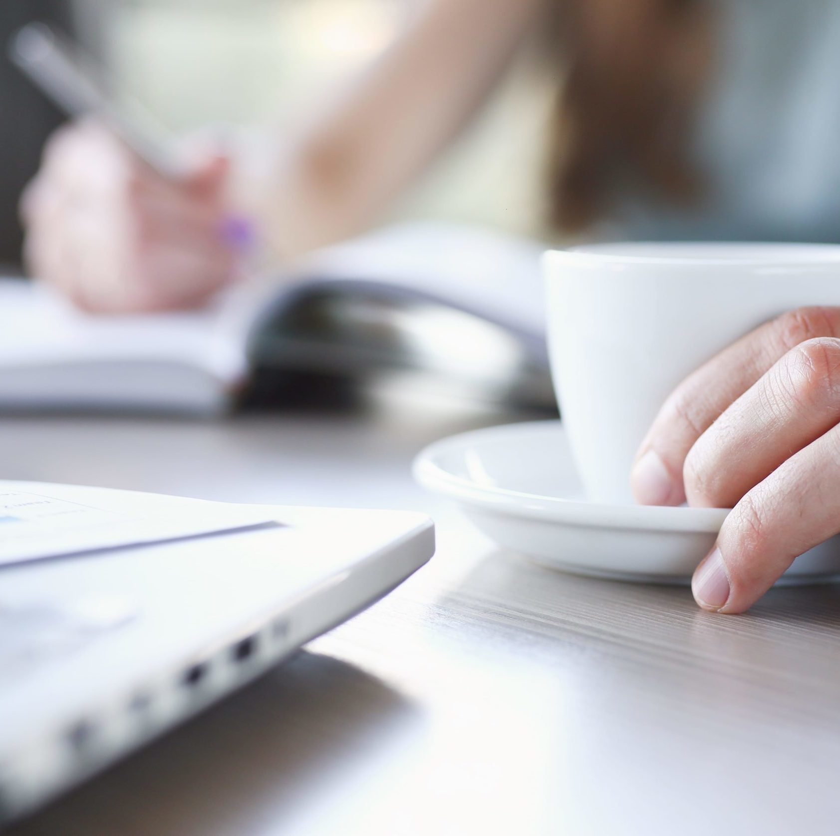 Hand holding coffe cup and other hand making notes