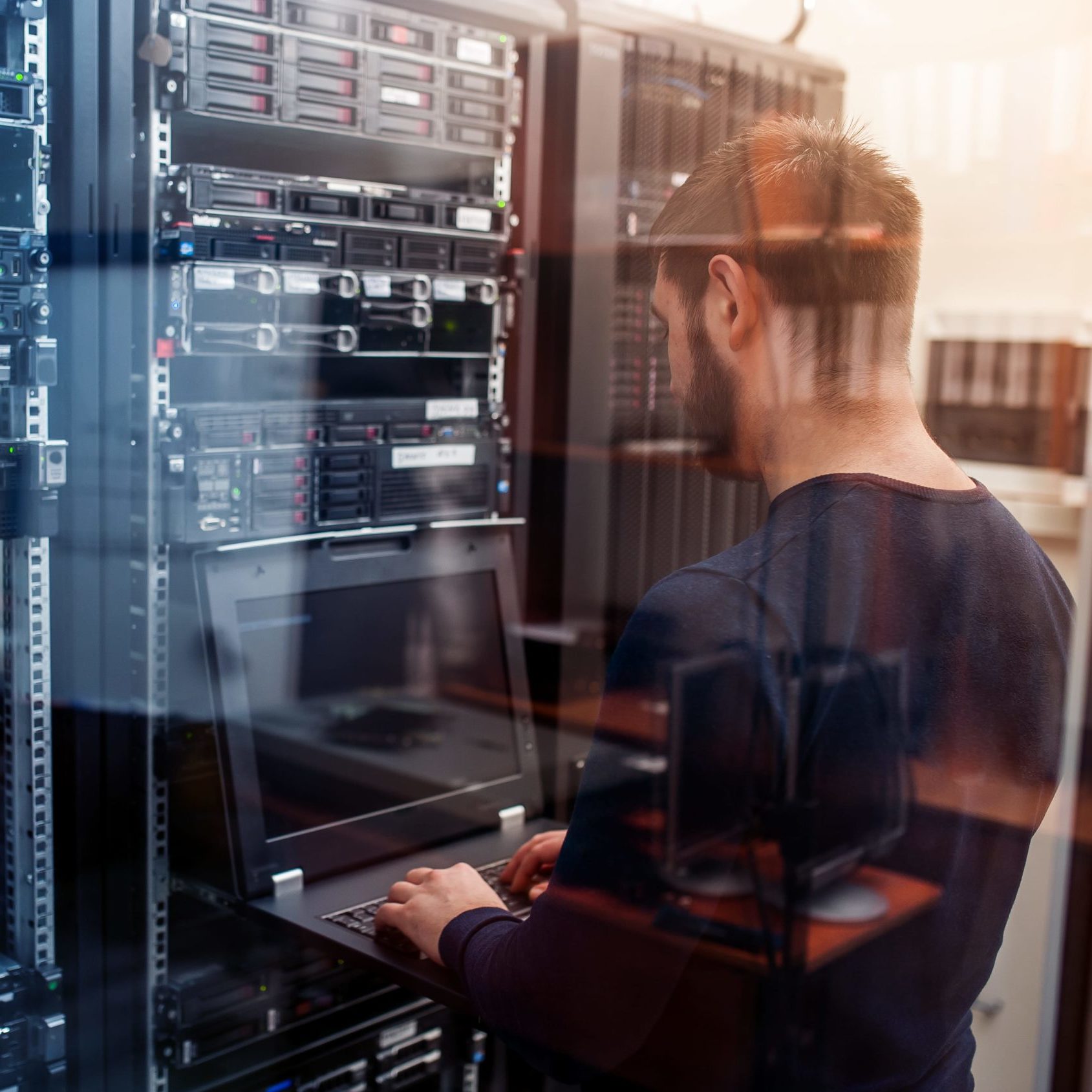 male engeneer with thin modern aluminium laptop in network server room